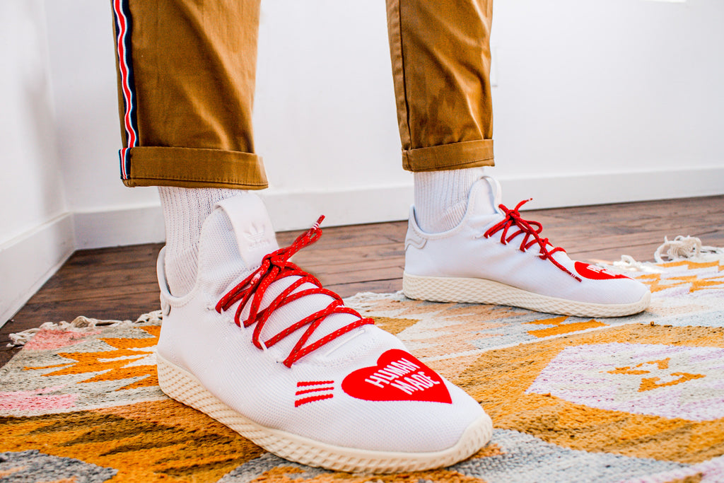 White shoes with red laces and a red heart on the toes that says "Human Made"